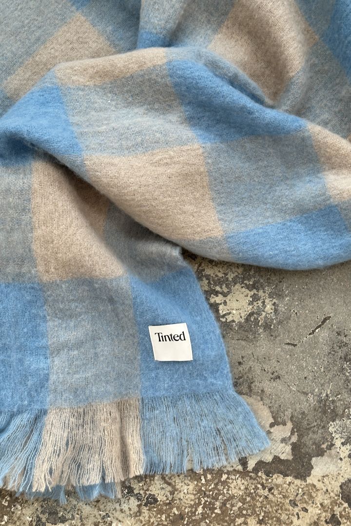 A blue and beige checked throw in wool from Swedish design brand Tinted. 