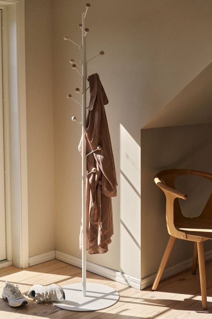 The Bill floor coat hanger bathed in sunlight in beige room. 