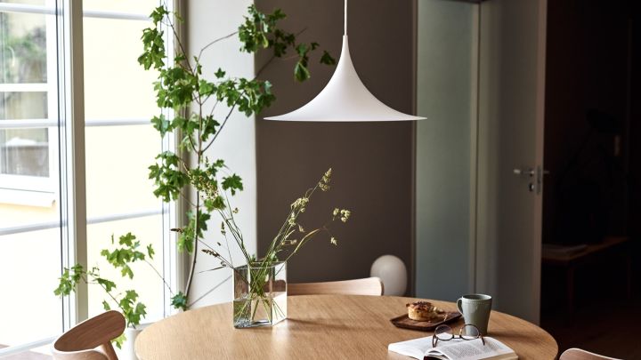 Discover GUBI's top tips for lighting your home. Here you see the Semi pendant lamp hanging over a dining table. 