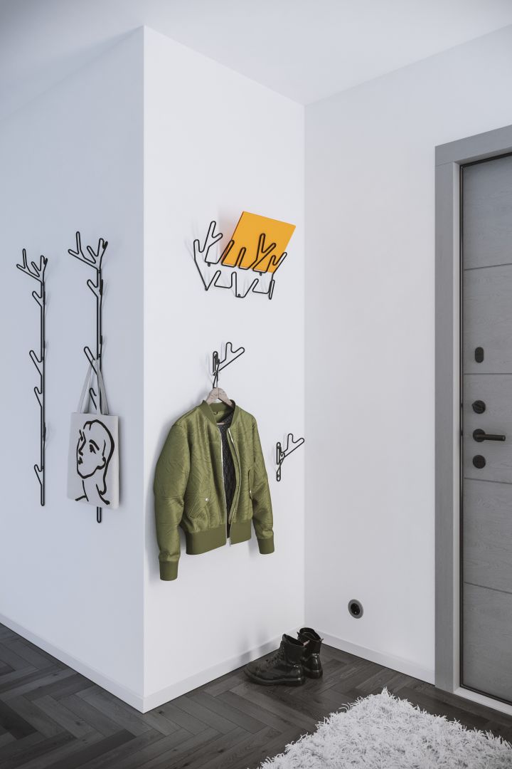 The Branch coat hanger from Maze with a green jacket and yellow folder in an open hallway. 