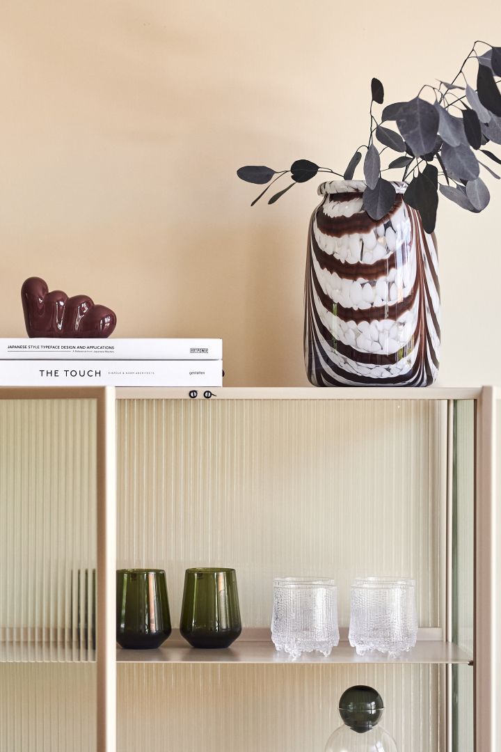 Interior design for 2022 is all about transparent details, here we see the Essence tumblers in moss green and the Ultima tumblers, both from Iittala in a glass case. 
