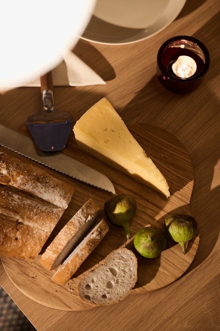 Crusty bread, figs and cheese stand on the wooden Alvar Aalto tray from Iittala as part of a Nordic Christmas celebration. 