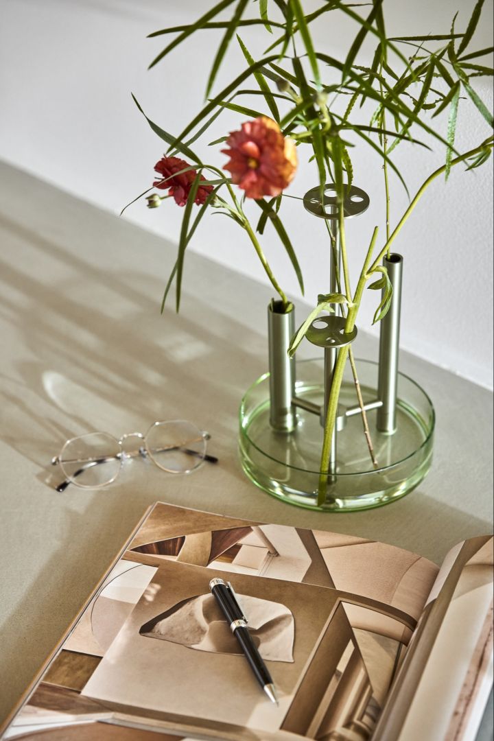 Here you see the Ikeru vase from Fritz Hansen, with red flowers in a soft light next to a magazine. 