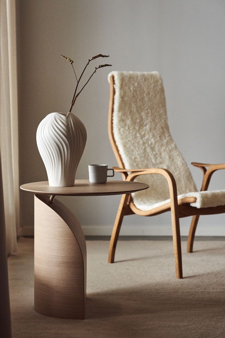 Here you see the Savoa table and the Lamino armchair with white sheepskin and oak wood from the Swedish furniture brand Swedese.