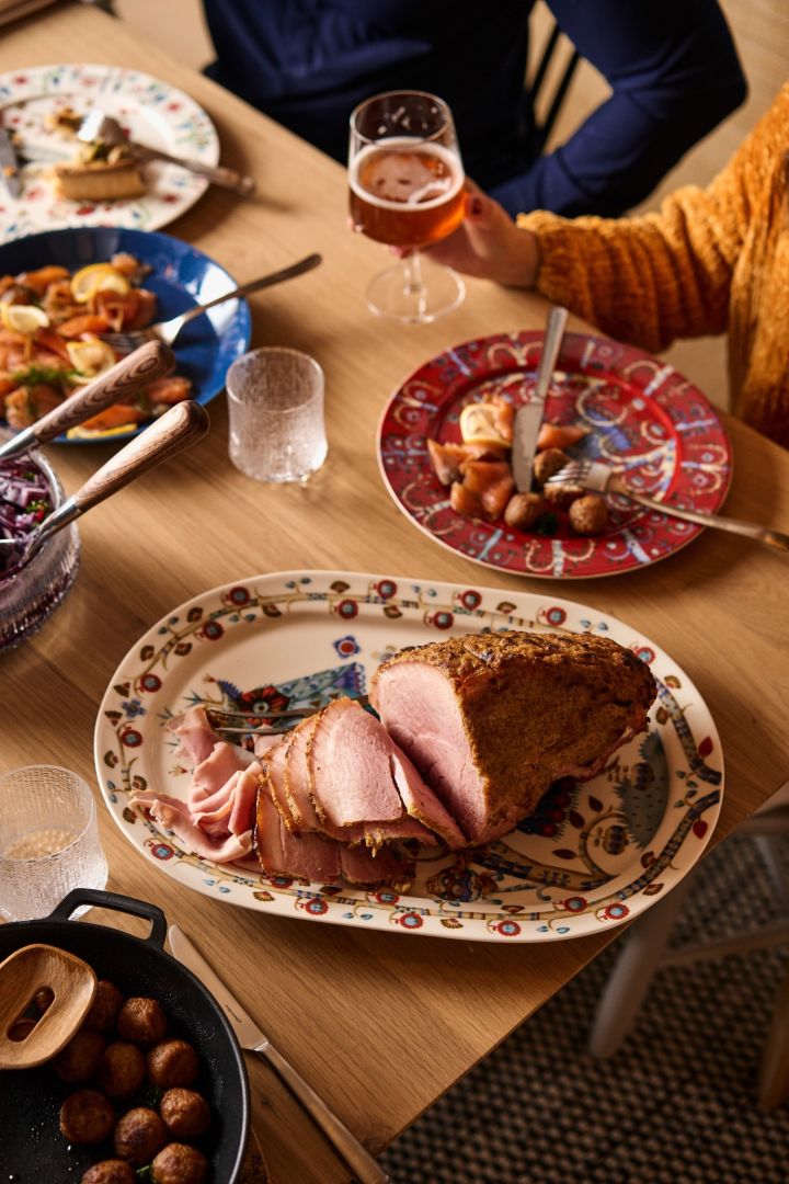 A sliced leg of ham stands on a traditional Nordic Christmas table. 