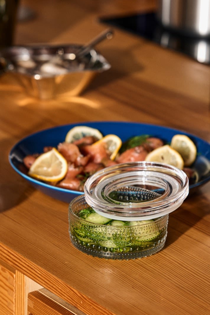 A jar of pickled cucumber on a Nordic Christmas table with gravlax in the background.