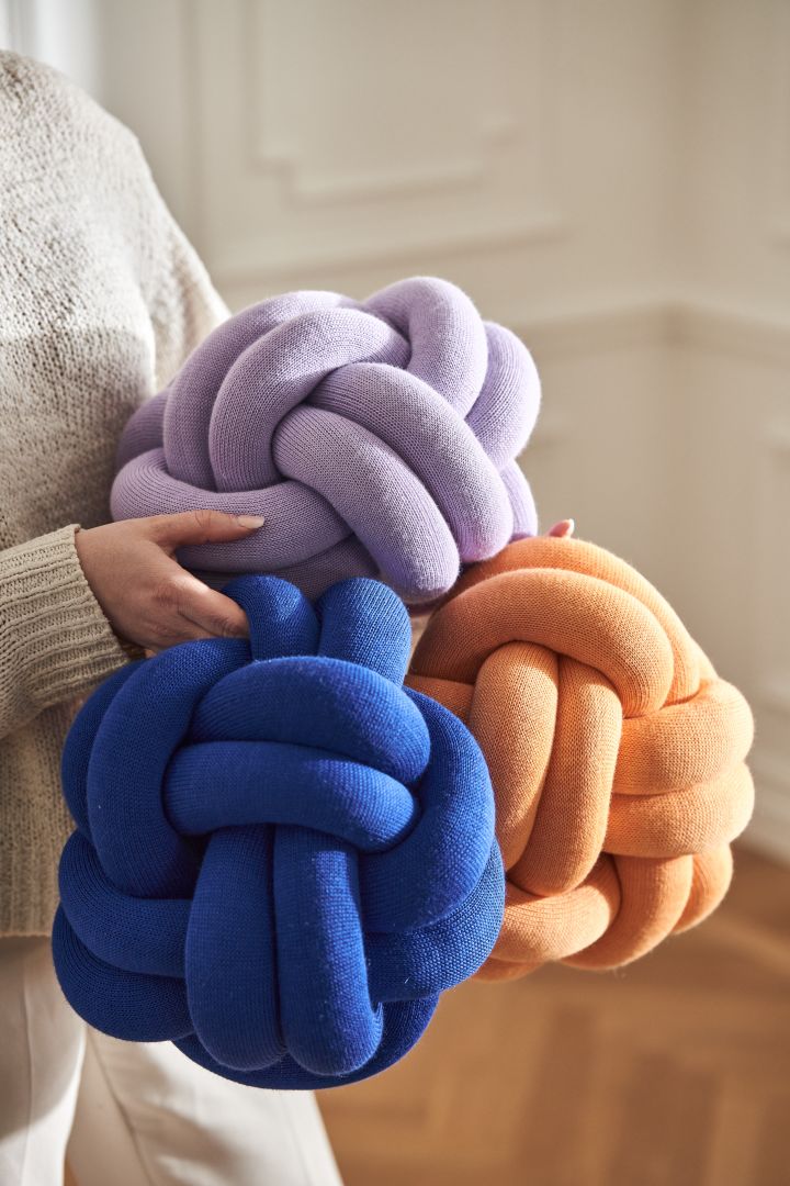 Knot cushions from Design House Stockholm in blue, purple and apricot in the arms of a woman.