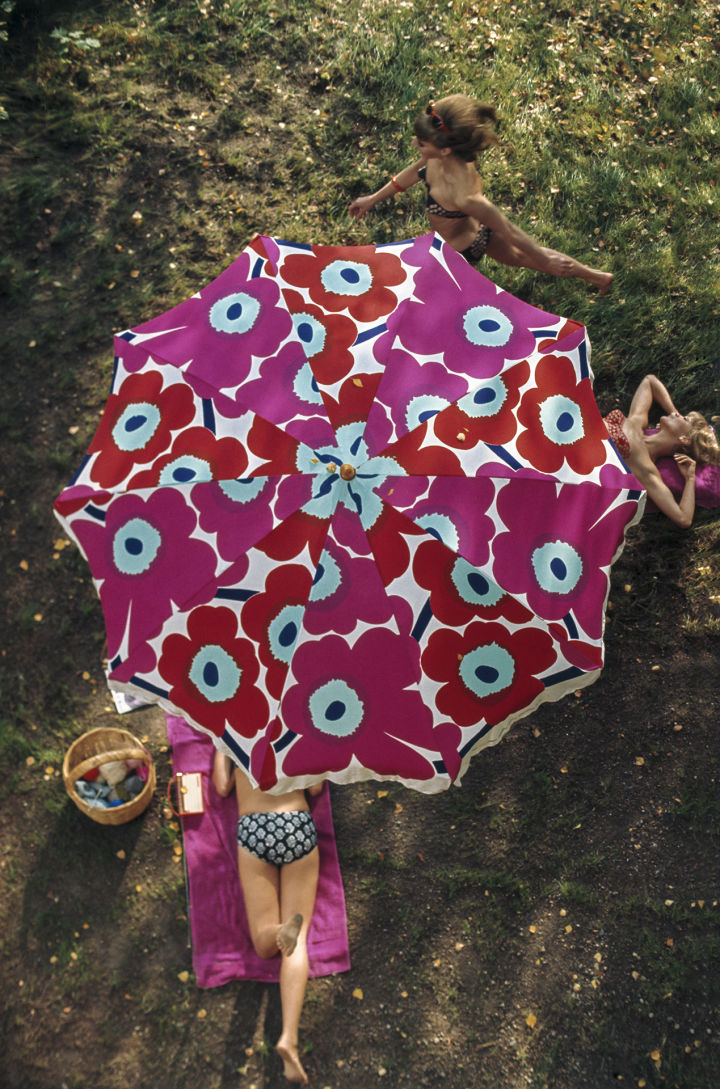 An image of a Unikko parasol from above with woman laying in the sunshine underneath. 