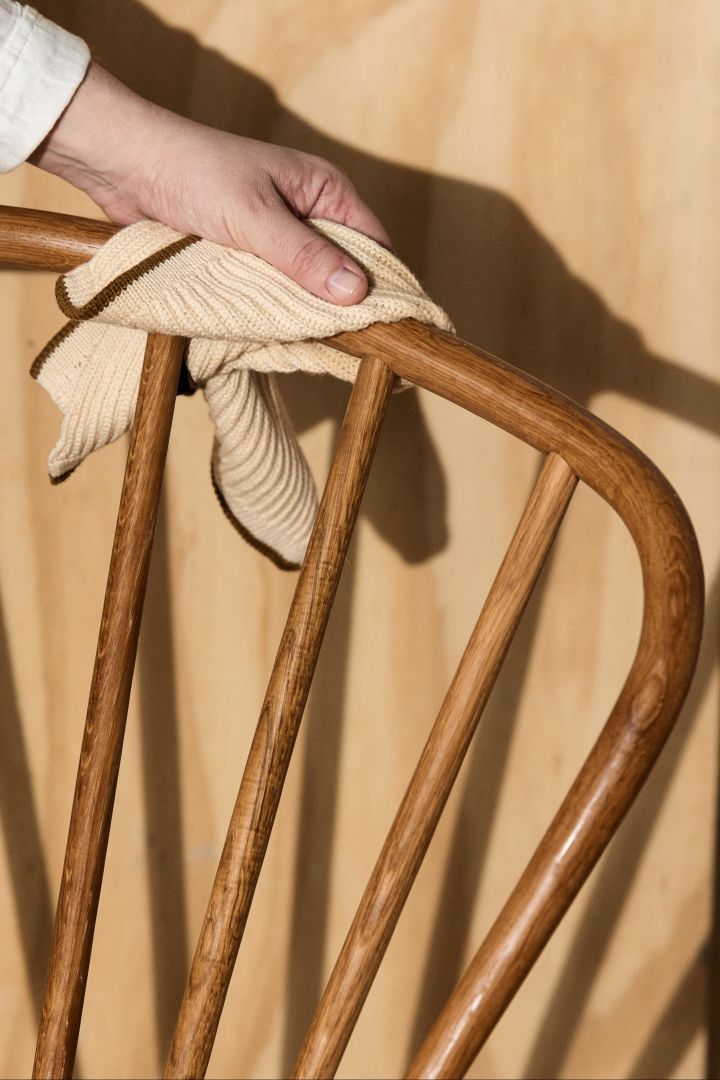 Here you see a hand cleaning a piece of teak furniture with a cloth. 