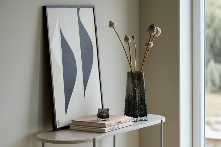 Here you see the Gry vase 30cm and the Gry candle lantern both in the colour Smoke from Cooee Design standing on a sideboard in front of a print.  