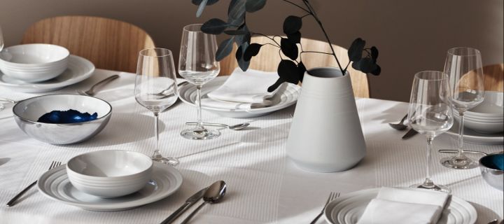 Wine glasses on a crisp white table setting with the NRJD plates and tableware. 