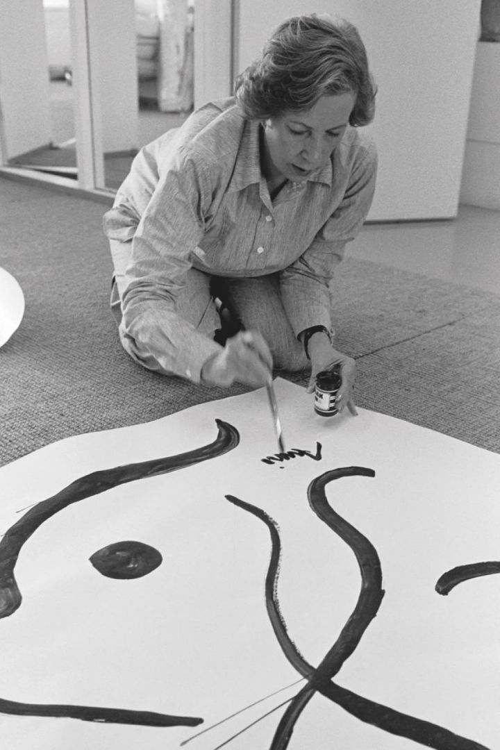 Armi Ratia, the founder of Marimekko signs her name at the bottom of a painting. 