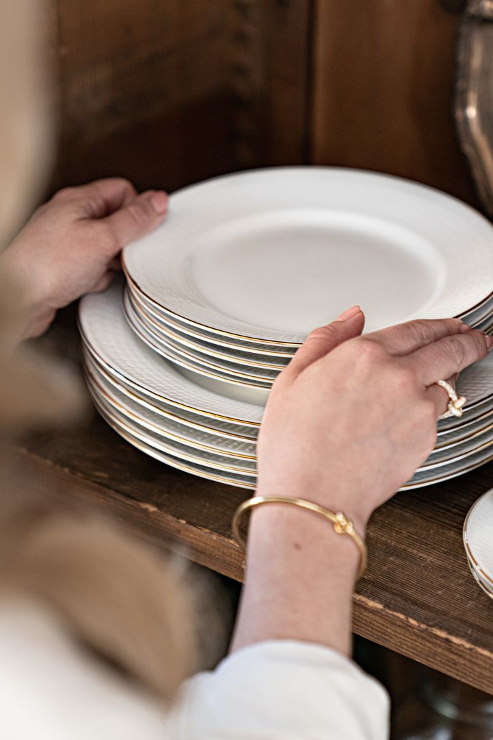 White plates with a golden rim from the Swedish Grace series Gala, stacked in a cupboard. 