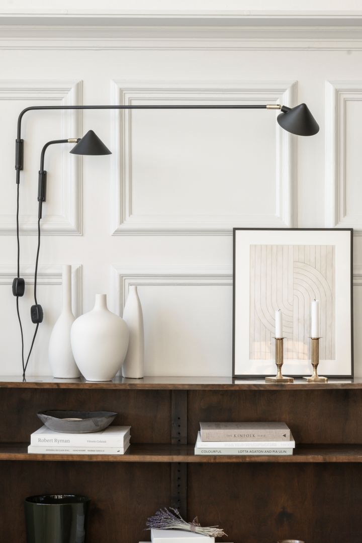 Refresh your home with modern lighting - here you see Kelly wall lamps in black from Watt & Veke next to vases and a painting.