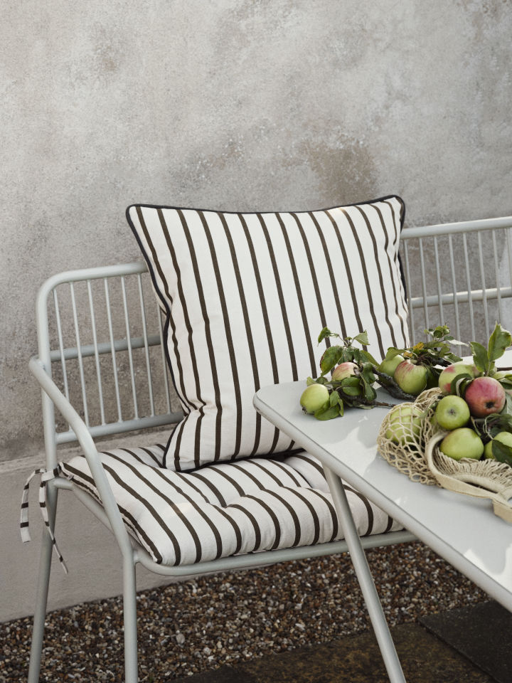 The outdoor Eden sofa from Broste Copenhagen in light grey stands on a small balcony.