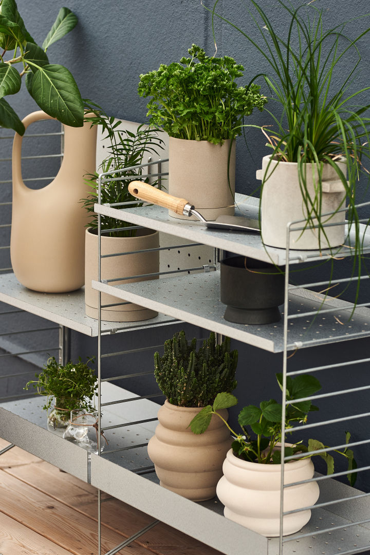 With the String Outdoor shelf system, you can build smart and stylish storage on your balcony. Here you see the shelves with lots of plant pots. 