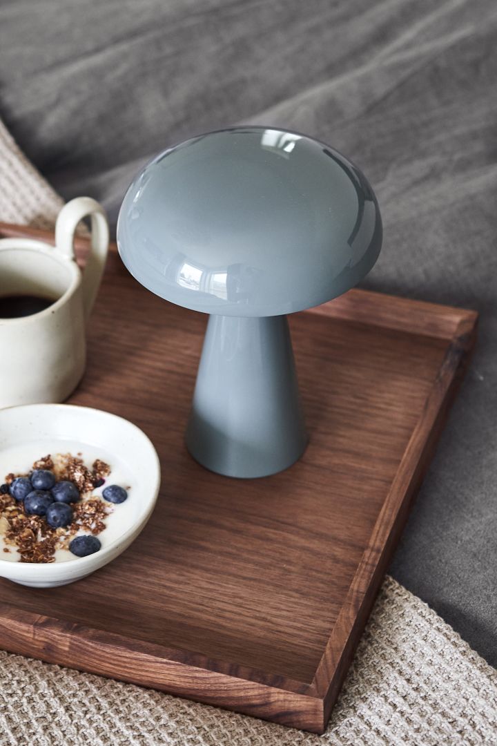 The portable and cordless Como lamp in stone blue from &tradition standing on a breakfast tray. 