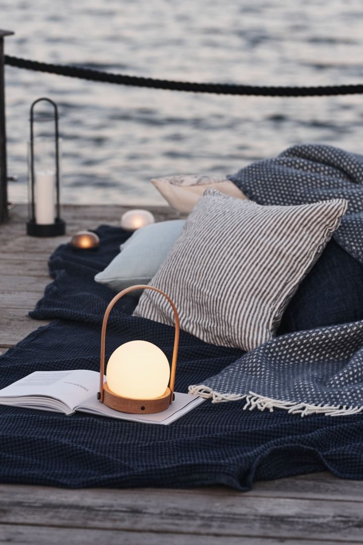 An atmospheric picnic by the sea with the cordless table lamp, Carrie from Audo Copenhagen. 